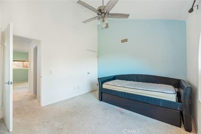 carpeted bedroom with ceiling fan and high vaulted ceiling