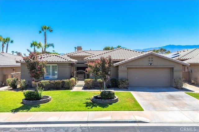 view of front of property featuring a garage, a mountain view, and a front lawn