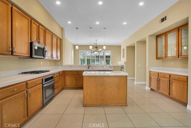 kitchen with pendant lighting, light tile patterned flooring, a center island, and appliances with stainless steel finishes