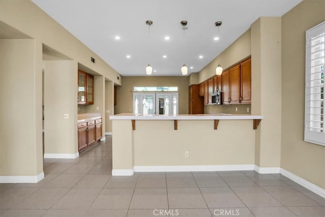 kitchen featuring light tile patterned flooring, a breakfast bar area, pendant lighting, and kitchen peninsula