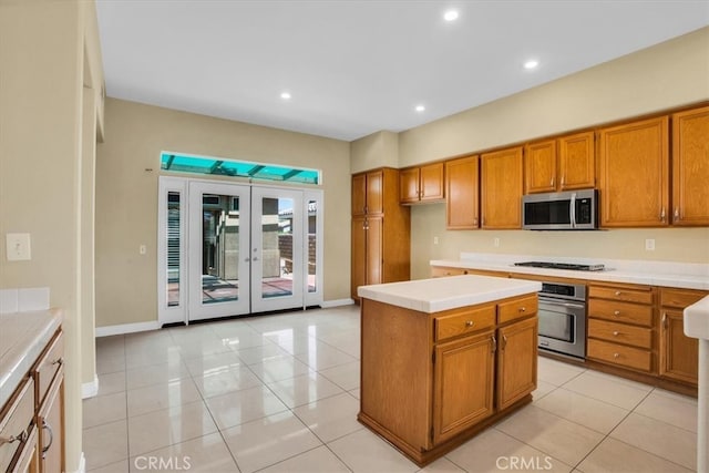 kitchen with french doors, stainless steel appliances, light tile patterned flooring, and a kitchen island