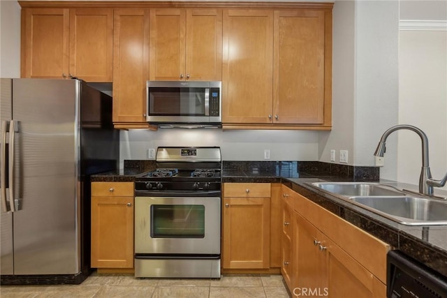 kitchen featuring sink, light tile patterned floors, dark stone counters, and appliances with stainless steel finishes