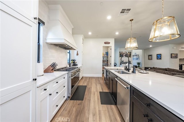 kitchen featuring stainless steel appliances, white cabinetry, hanging light fixtures, and sink