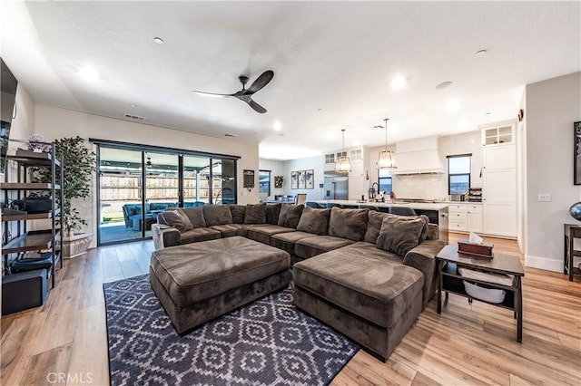 living room with light hardwood / wood-style flooring and ceiling fan