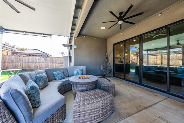 view of patio with ceiling fan and an outdoor living space with a fire pit