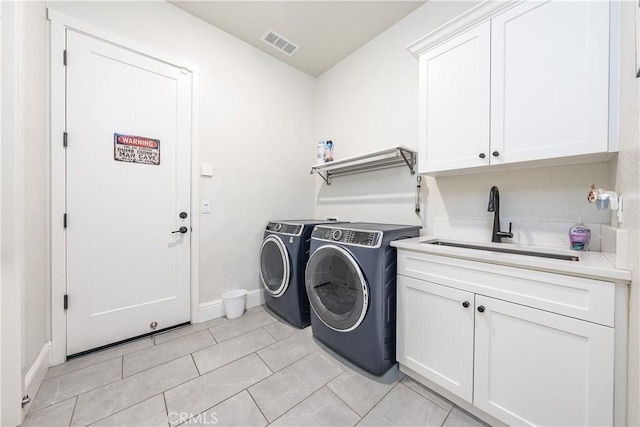 laundry area with cabinets, washing machine and dryer, sink, and light tile patterned flooring