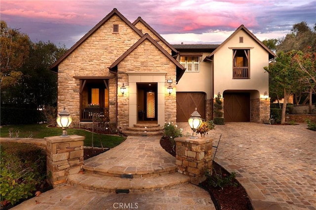 view of front facade featuring a garage, a balcony, decorative driveway, and stucco siding