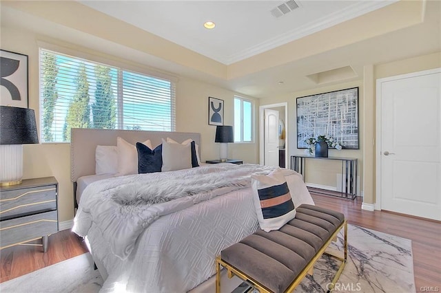 bedroom featuring wood-type flooring, crown molding, and a tray ceiling