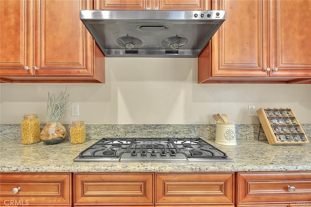 kitchen featuring stainless steel gas cooktop, light stone countertops, and extractor fan