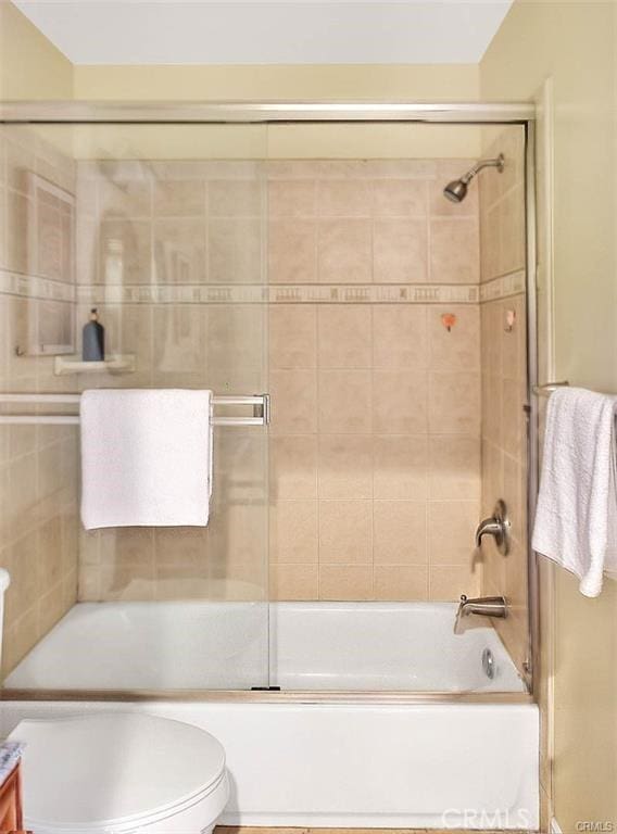 full bathroom featuring vanity, shower / bath combination with glass door, and toilet