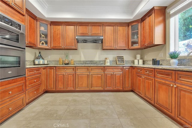 kitchen featuring light stone counters, light tile patterned floors, ornamental molding, double oven, and black stovetop