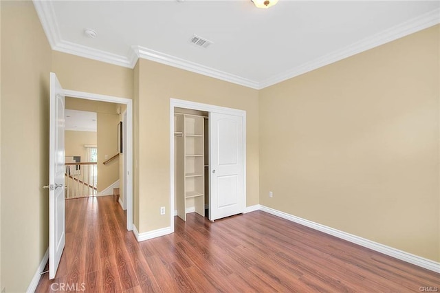 unfurnished bedroom featuring dark wood-type flooring, ornamental molding, and a closet