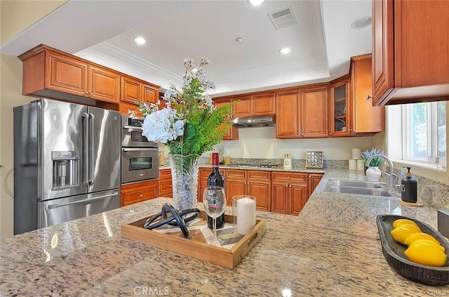 kitchen featuring sink, stainless steel appliances, a tray ceiling, ornamental molding, and kitchen peninsula