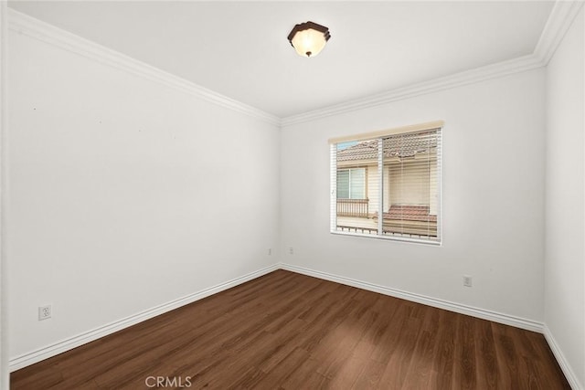 spare room with dark wood finished floors, baseboards, and ornamental molding