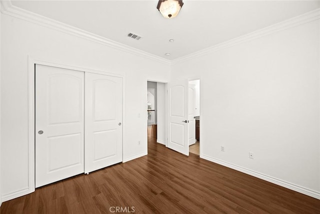 unfurnished bedroom featuring dark wood finished floors, visible vents, ornamental molding, a closet, and baseboards