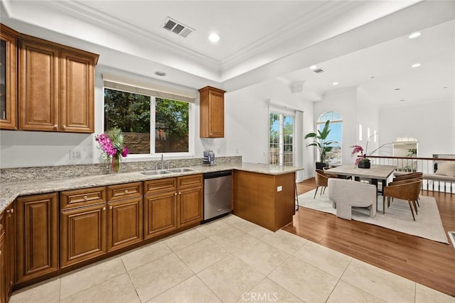 kitchen featuring dishwasher, visible vents, a sink, and brown cabinets