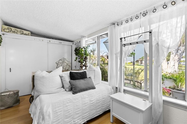 bedroom with access to outside, wood-type flooring, and a textured ceiling