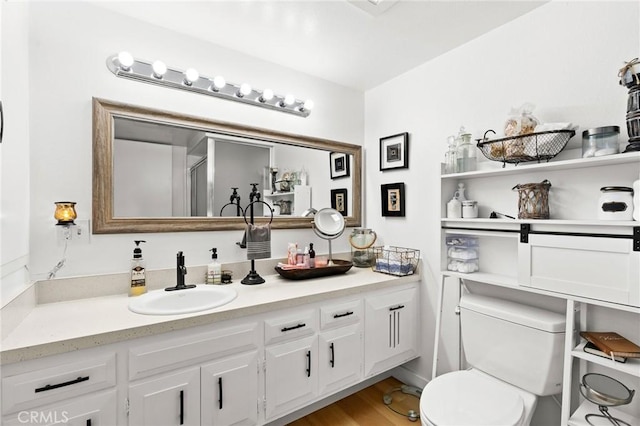 bathroom with hardwood / wood-style flooring, toilet, vanity, and an enclosed shower