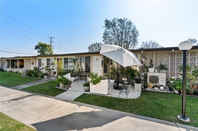 exterior space with ac unit, a patio area, and a lawn