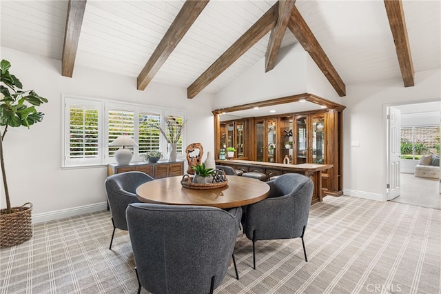 dining area with lofted ceiling with beams, a wealth of natural light, and light colored carpet