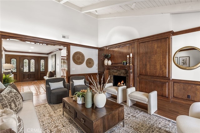 living room featuring beamed ceiling, a towering ceiling, a fireplace, and light hardwood / wood-style flooring