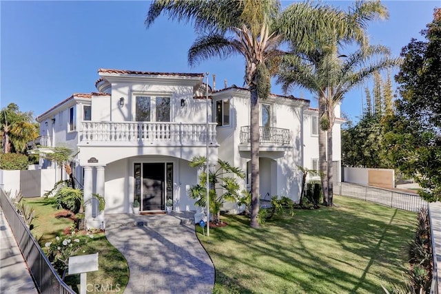 mediterranean / spanish house featuring a balcony and a front lawn