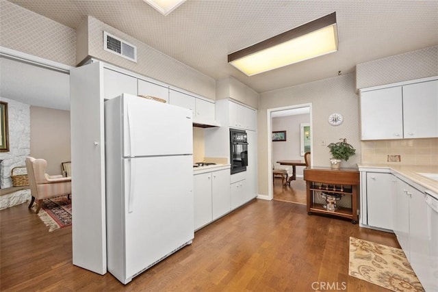 kitchen featuring black oven, white cabinets, and white refrigerator