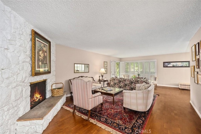 living room featuring a stone fireplace, hardwood / wood-style floors, and a textured ceiling