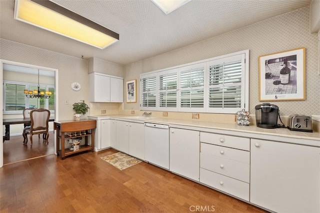 kitchen featuring pendant lighting, white cabinetry, dark hardwood / wood-style floors, white dishwasher, and a chandelier