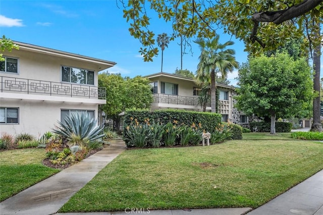 view of front of home with a balcony and a front lawn