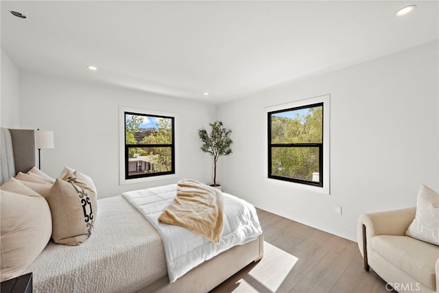 bedroom featuring multiple windows, wood finished floors, recessed lighting, and baseboards