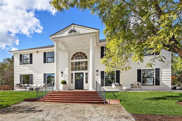 greek revival inspired property with a front lawn and an outdoor living space