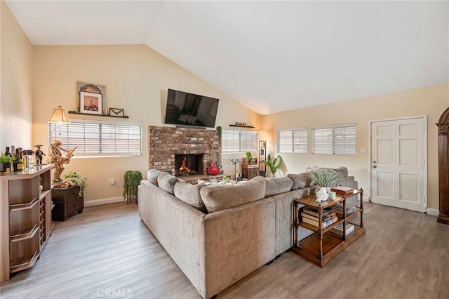 living room featuring lofted ceiling, a fireplace, and light wood-type flooring