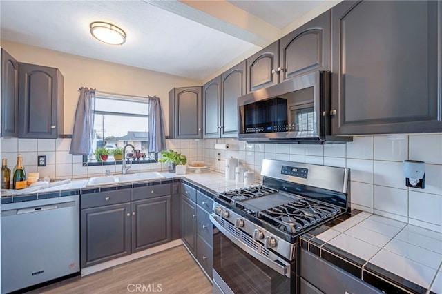 kitchen featuring tasteful backsplash, sink, tile counters, and stainless steel appliances