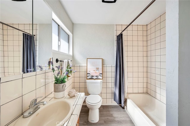 full bathroom with wood-type flooring, tile walls, shower / bath combination with curtain, vanity, and toilet