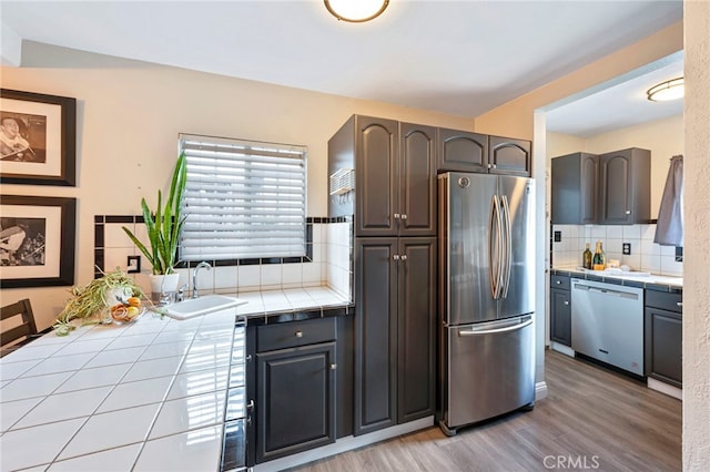 kitchen featuring tasteful backsplash, sink, tile counters, and appliances with stainless steel finishes