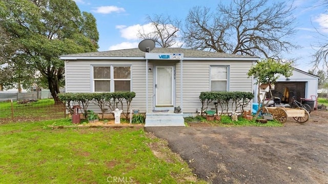 view of front of house featuring a garage, an outdoor structure, and a front lawn