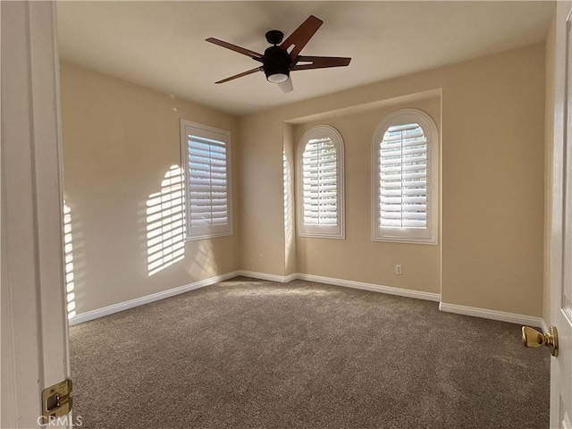 carpeted empty room featuring baseboards and a ceiling fan