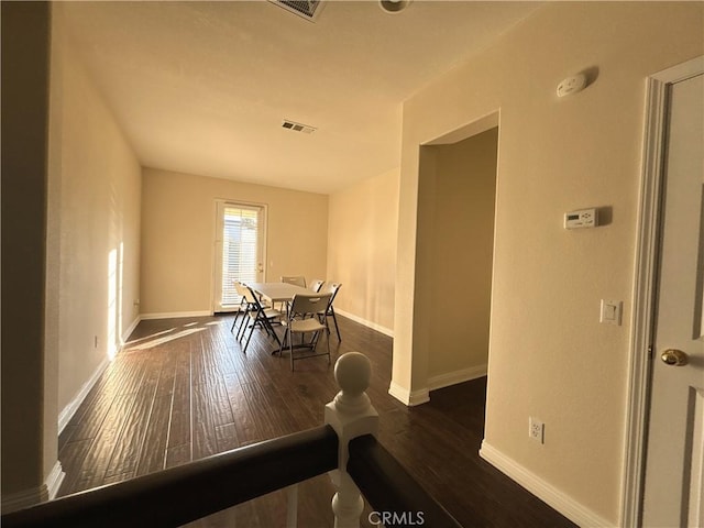 dining room with dark wood-type flooring, visible vents, and baseboards