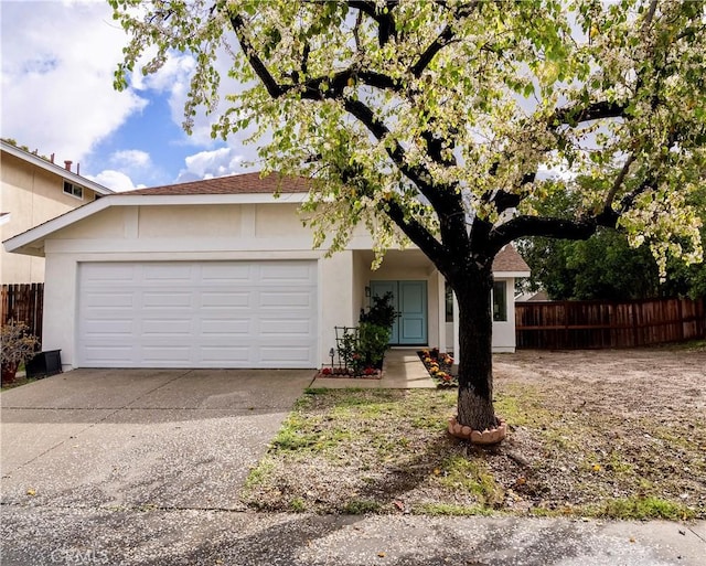 ranch-style house featuring a garage, fence, concrete driveway, and stucco siding