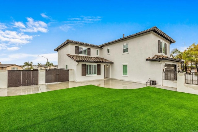 rear view of property with a tile roof, a lawn, a gate, a patio area, and fence