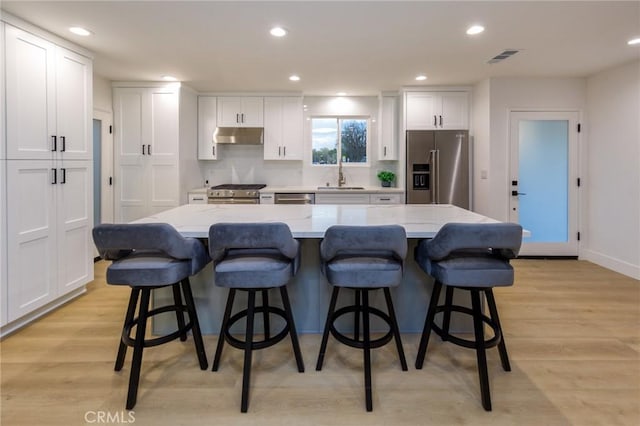 kitchen with high quality appliances, a large island, a breakfast bar, and white cabinets