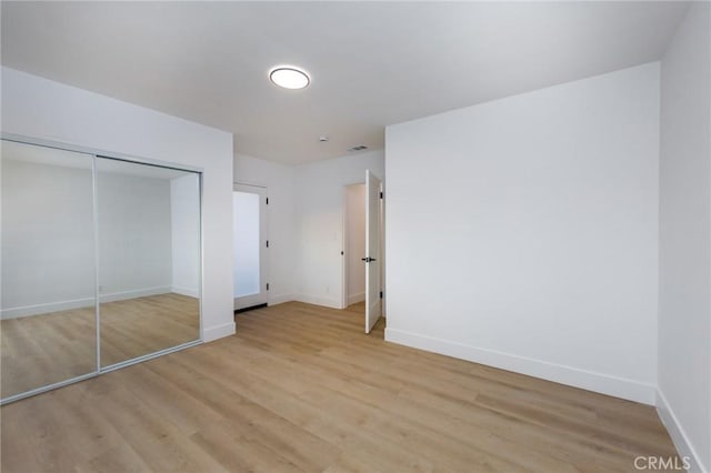 unfurnished bedroom featuring light hardwood / wood-style flooring and a closet