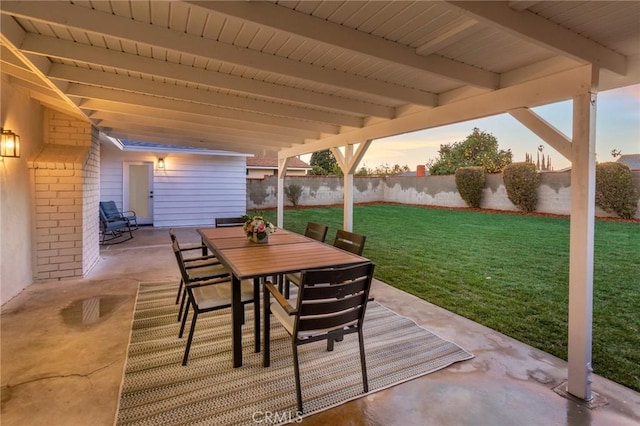 patio terrace at dusk featuring a lawn