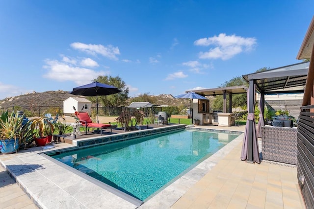 pool with a patio, outdoor dry bar, an outdoor kitchen, a gazebo, and fence