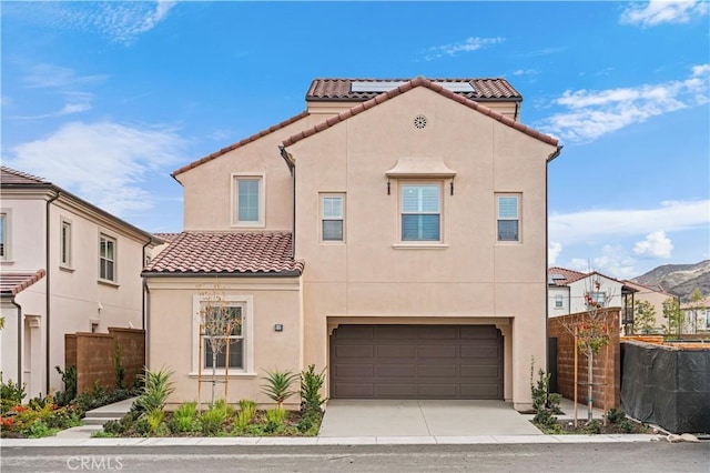 mediterranean / spanish-style house with a tile roof, stucco siding, fence, a garage, and driveway