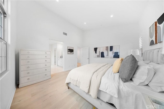 bedroom with a towering ceiling and light hardwood / wood-style floors