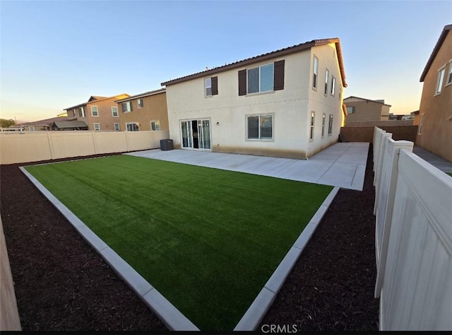 back house at dusk with a yard and a patio area