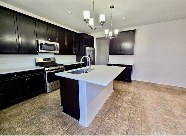 kitchen featuring appliances with stainless steel finishes, hanging light fixtures, a notable chandelier, an island with sink, and sink