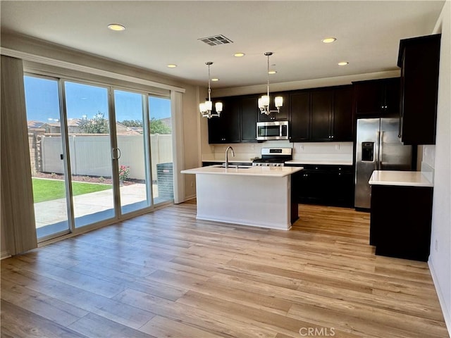 30750 Gazing Star Ln, Murrieta, CA 92563 - kitchen featuring appliances with stainless steel finishes, a chandelier, light countertops, light wood finished floors, and hanging light fixtures